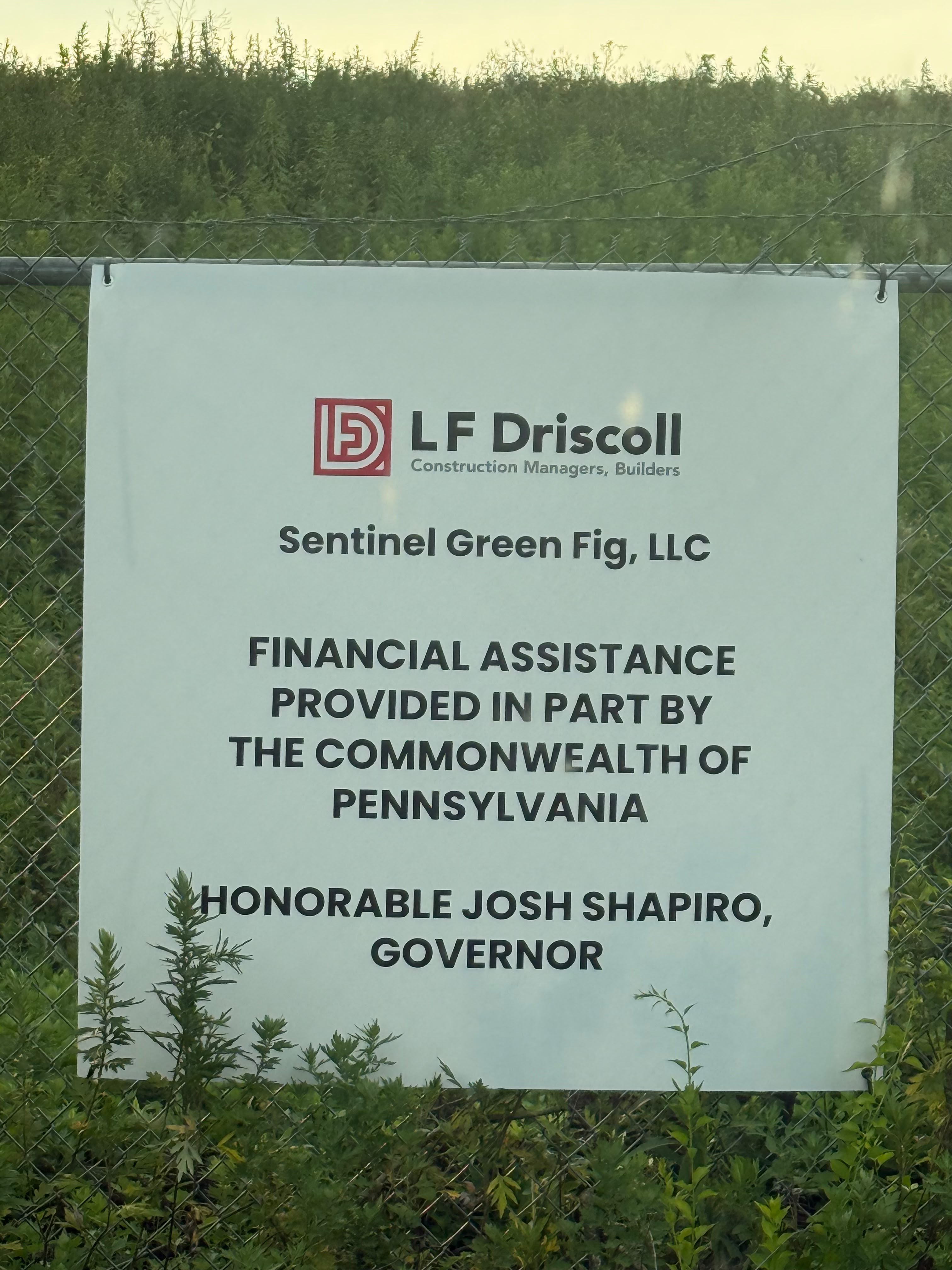 A construction site sign reading 'Sentinel Green Fig, LLC. Financial assistance provided in part by the Commonwealth of Pennsylvania. Honorable Josh Shapiro, Governor.'